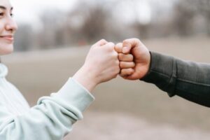 man and happy woman greeting each other with fist bump